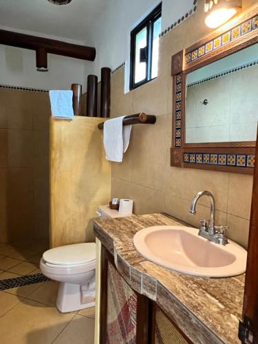 uma casa de banho com um lavatório, um WC e um espelho. em Villa el Arca em Zihuatanejo