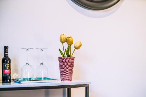 a vase with flowers on a table with wine glasses at Marmur luxury room in Lecce