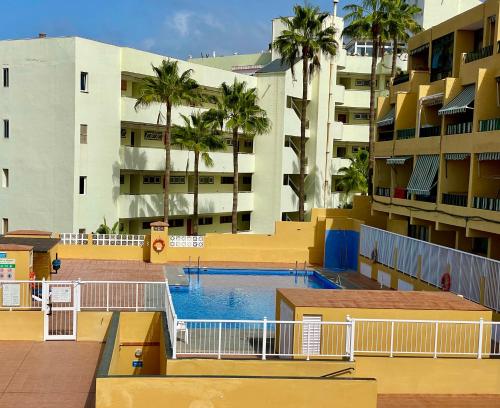 una piscina frente a un edificio con palmeras en Vista La Gomera - 2 minutes walk from the beach!, en Puerto de Santiago