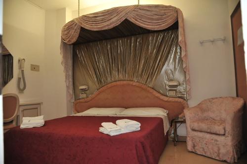 a bedroom with a canopy bed and a chair at Hotel Baia Marina in Cattolica