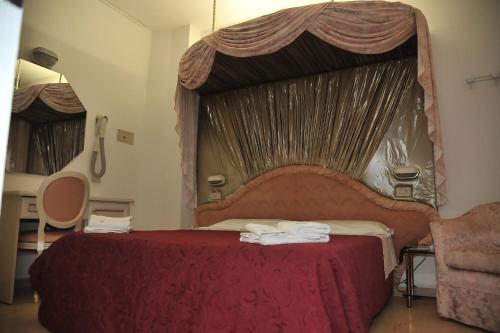 a bedroom with a large red bed with a canopy at Hotel Baia Marina in Cattolica