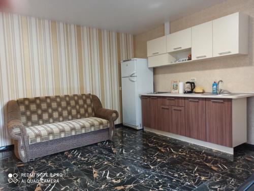 Habitación con sofá y cocina con nevera. en Нова квартира, en Poltava