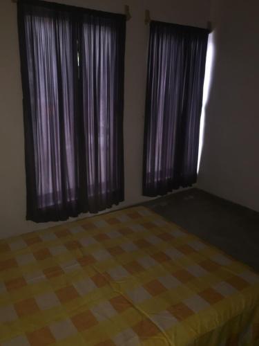 um quarto com 2 grandes janelas com cortinas roxas em Hostal La Piedra em Matlapa
