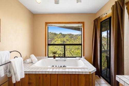 a bathroom with a large tub and a window at Spicewood Treehouse in Spicewood