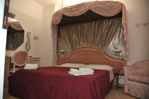 a bedroom with a red bed with a canopy at Hotel Baia Marina in Cattolica