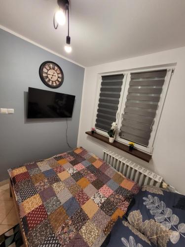 een slaapkamer met een bed en een klok aan de muur bij Apartament Leon in Wałbrzych
