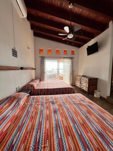 a large bedroom with two beds and a ceiling fan at Villa el Arca in Zihuatanejo