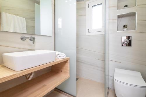 La salle de bains est pourvue d'un lavabo blanc et de toilettes. dans l'établissement Spartakos Luxury Villa 1, à Planos