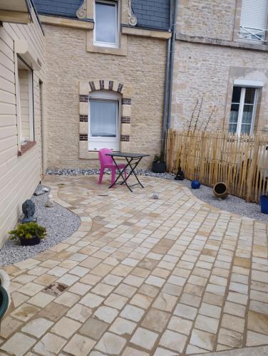 een patio met een roze stoel voor een gebouw bij Chambre d'hôtes sur les plages du débarquement in Ver-sur-Mer