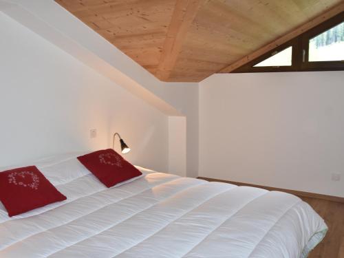 une chambre avec un lit blanc avec des oreillers rouges dans l'établissement Appartement Duplex Neuf 4 Pièces avec Balcon, Proche Téléphérique et Centre Aqualudique - FR-1-464-210, à Pralognan-la-Vanoise