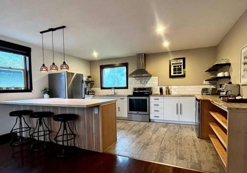a kitchen with white cabinets and a island with bar stools at Two Bedroom House by Snow Valley Lodging in Fernie