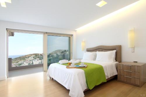 a bedroom with a large bed and a large window at Villa Nelmar in Anavyssos