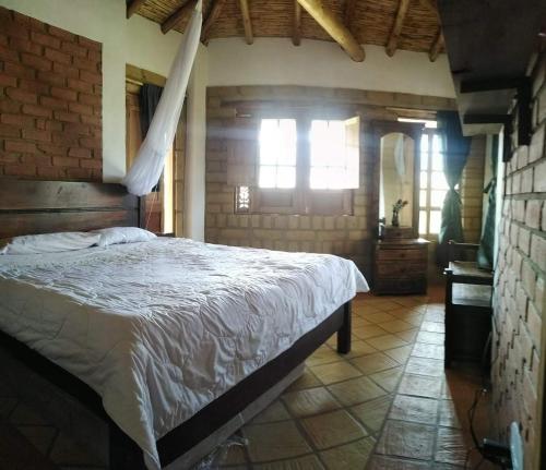 1 dormitorio con cama y pared de ladrillo en Hermoso lugar familiar cerca a Villa de Leyva en Sutamarchán