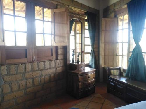 a bedroom with a dresser and a desk and windows at Hermoso lugar familiar cerca a Villa de Leyva in Sutamarchán