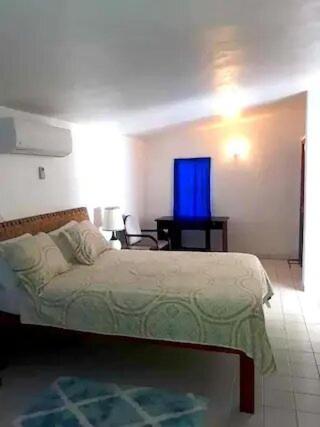 Un dormitorio con una cama y una mesa con una ventana azul. en Villa Kaiae en Sandy Ground Village
