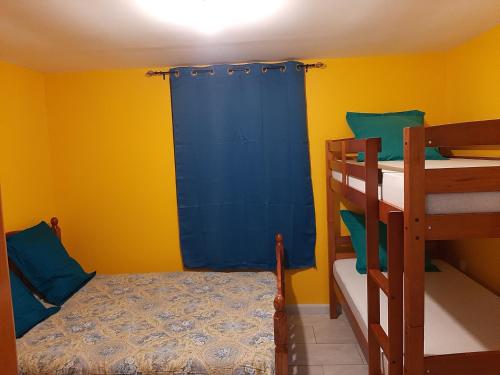 1 dormitorio con 2 literas y cortina azul en Pomme de Pin, en Cilaos