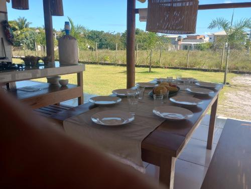 uma longa mesa de madeira com pratos e copos em Casa D´Alicia em Maraú