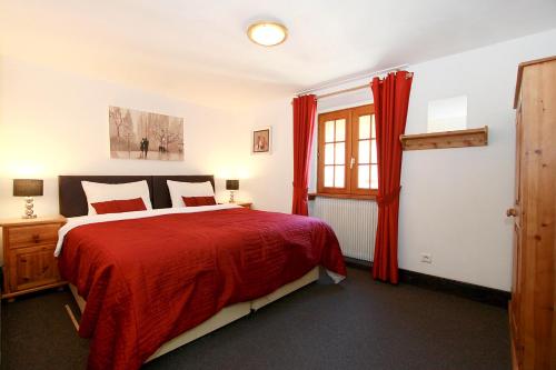 a bedroom with a bed with red sheets and a window at Chalet Ruby in Les Deux Alpes