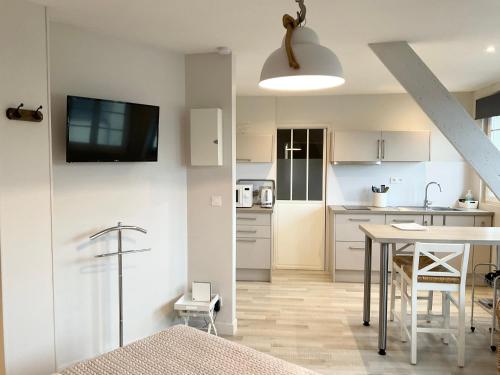Il comprend une cuisine et une salle à manger avec une table et une télévision murale. dans l'établissement Mon Port d'Attache, à Port-en-Bessin-Huppain