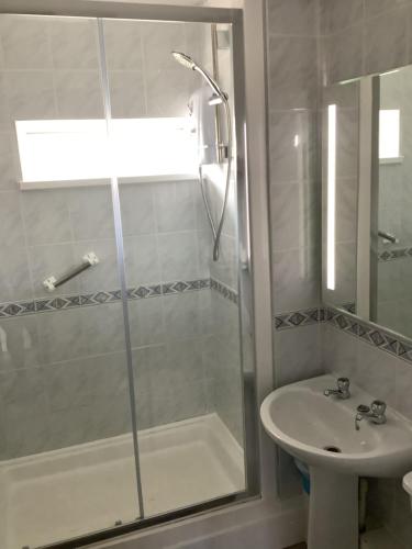 La salle de bains est pourvue d'une douche et d'un lavabo. dans l'établissement Surf View Apartments, à Newquay