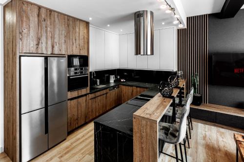 a kitchen with a stainless steel refrigerator and wooden cabinets at Ratusz Exclusive Apartment- Apartament przy Ratuszu in Głogów