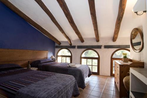 a bedroom with two beds and two windows at Mas D'en Gregori in Porrera