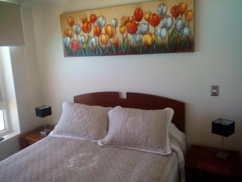 1 dormitorio con 1 cama con una pintura en la pared en Departamento Resort Laguna del Mar, en La Serena