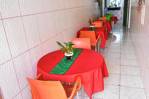 una fila de mesas con sillas rojas y naranjas en Pousada Aconchego, en São Luís