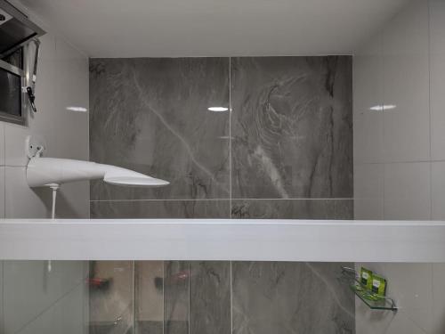 La salle de bains est pourvue d'une douche et d'un mur en marbre. dans l'établissement Ipê Suítes, à Domingos Martins