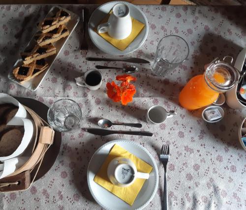 einen Tisch mit Teller mit Lebensmitteln auf einem weißen Tischtuch in der Unterkunft PANEERIPOSO in Pergine Valsugana