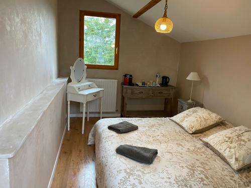 a bedroom with a bed and a table and a window at Maison Zen et Cosy avec Bulle pour dormir à la belle étoile & Jacuzzi in Vif