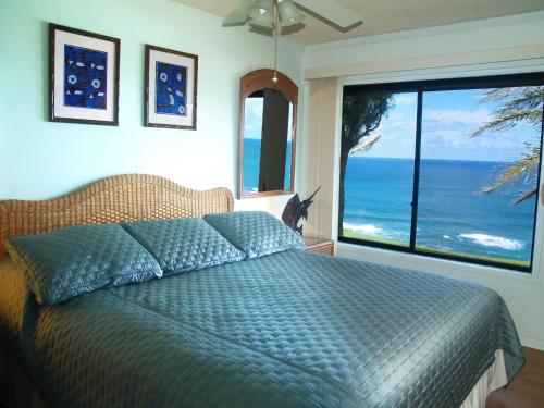 a bedroom with a bed with a view of the ocean at Princeville Sealodge Unit D-4 in Princeville