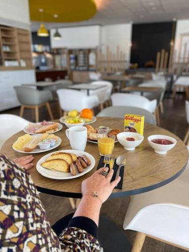 a person sitting at a table with plates of food at Holiday Inn Express - Paris - CDG Airport by IHG in Roissy-en-France