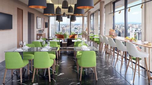 un restaurant avec des chaises vertes et un bar avec vue dans l'établissement Holiday Inn Santo Domingo, an IHG Hotel, à Saint-Domingue