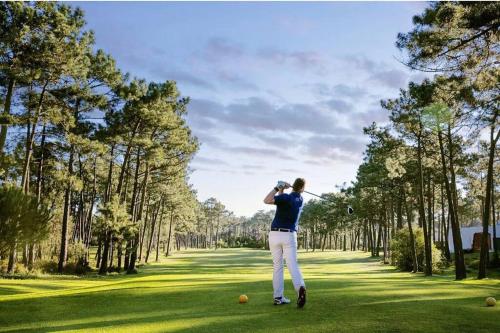 a man swinging a golf club on a golf course at Charmoso apartamento na Herdade da Aroeira in Aroeira