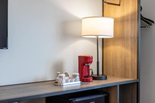 a red coffee maker on a table with a lamp at The Lodge Red Hook in Brooklyn