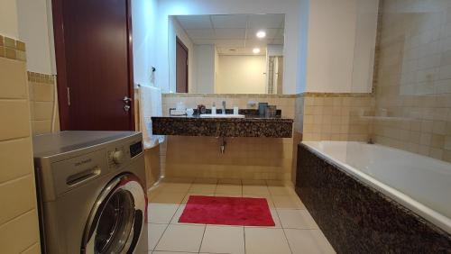 a bathroom with a sink and a washing machine at Modern, Luxe & Spacious 4-Bed Condo, Full Kitchen, 3 Min walk to Beach, Tram & Marina By "La Buena Vida Holiday Homes" in Dubai