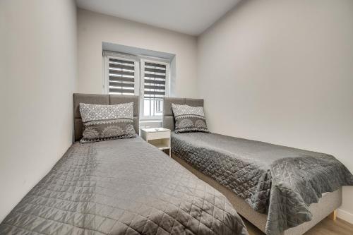 two beds in a bedroom with a window at Central Platinum Apartments 22 in Rybnik