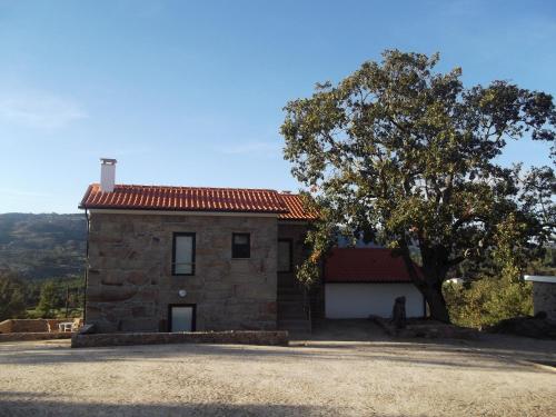 a stone house with a tree in front of it at Quinta dos Carvalhais - Serra da Estrela in Fornos de Algodres