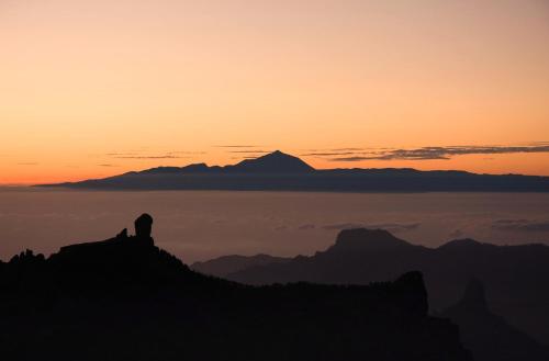 a silhouette of a mountain with a sunset in the background at Acogedor y cómodo apartamento con piscina in Las Palmas de Gran Canaria