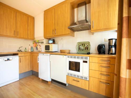 a kitchen with wooden cabinets and white appliances at Comfy holiday home in Hoorn with French balcony in Hoorn