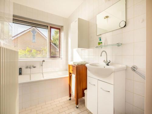 un bagno bianco con lavandino, vasca e lavandino di Comfy holiday home in Hoorn with French balcony a Hoorn