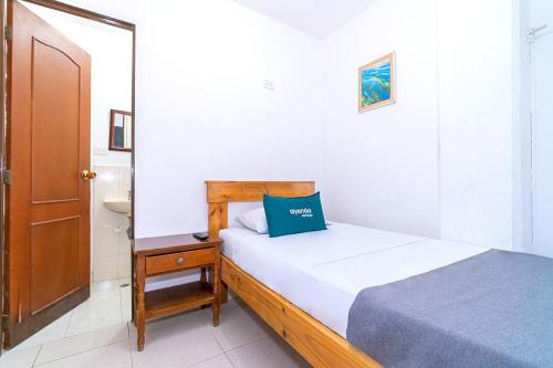 a bedroom with a bed with a blue pillow on it at HOTEL HOSPEDAJE CANEY "Descanso & Tradición" Ayenda 1422 in Cali