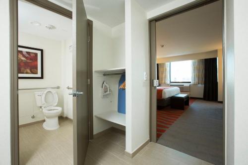 a bathroom with a toilet and a room with a bed at Holiday Inn Houston S - NRG Area - Med Ctr, an IHG Hotel in Houston