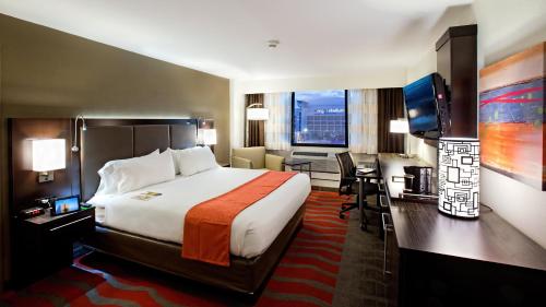 um quarto de hotel com uma cama grande e uma secretária em Holiday Inn Houston S - NRG Area - Med Ctr, an IHG Hotel em Houston
