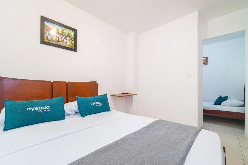 1 dormitorio con cama blanca y almohadas azules en HOTEL HOSPEDAJE CANEY "Descanso & Tradición" Ayenda 1422, en Cali