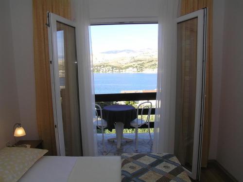 a bedroom with a view of the ocean from a balcony at Apartments Pavicic Marija in Pag