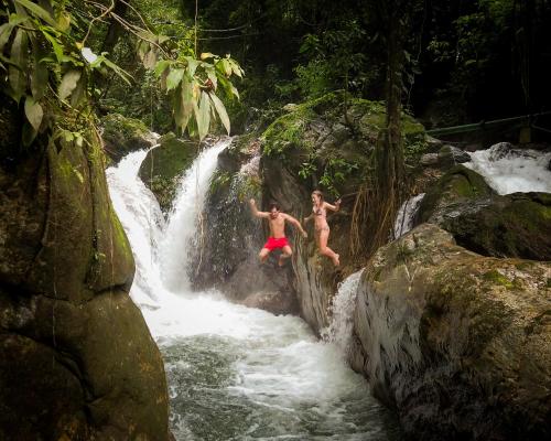 Zwei Jungs springen von einem Wasserfall in einen Fluss in der Unterkunft ECO Cabin - TANOA Minca in Minca