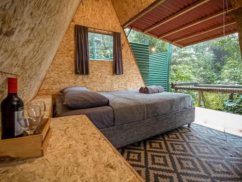a bedroom with a bed and a table with a bottle of wine at ECO Cabin - TANOA Minca in Minca