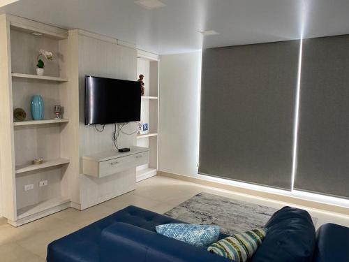 a living room with a blue couch and a flat screen tv at Alquilo hermoso departamento en Salinas, Ecuador in Salinas
